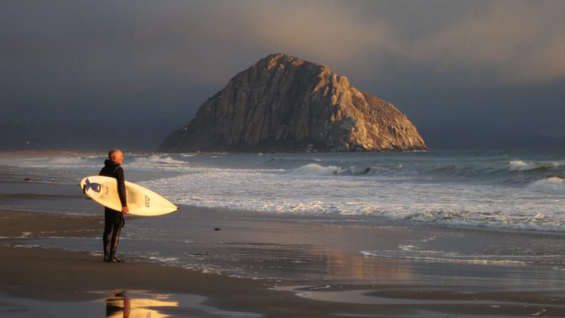 Un surfista contempla el Océano Pacífico mientras Morro Rock se encuentra bajo el sol vespertino en Morro Bay, California, el 8 de julio de 2014. (Sean Gallup/Getty Images)