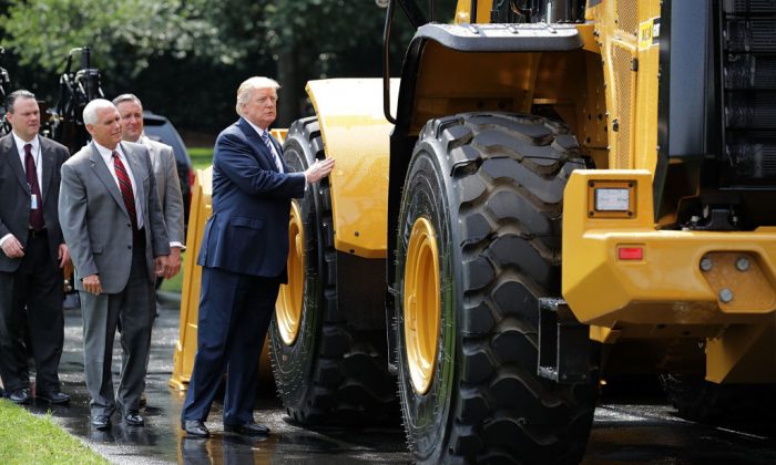 El Presidente de EE.UU. Donald Trump toca una cargadora de ruedas fabricada por Caterpillar mientras recorre una muestra de productos Made in America con el vicepresidente Mike Pence en el jardín sur de la Casa Blanca en Washington el 17 de julio de 2017 (Chip Somodevilla/Getty Images)