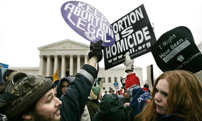 La activista pro-vida Jessica Meunier (R) de Fitchburg, MA, y el activista pro-aborto Luqman Clark (L) de Arlington, VA, sostienen carteles mientras protestan frente a la Corte Suprema de los Estados Unidos durante el evento "Marcha por la vida" 24 de enero de 2005 en Washington DC Imágenes de Alex Wong / Getty images