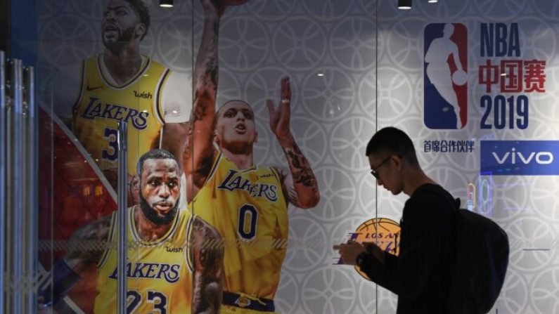 Homem passa por um anúncio de jogos de exibição programados na China entre o LA Lakers e o Brooklyn Nets, na loja da National Basketball Association (NBA) em Pequim, em 9 de outubro de 2019 (Greg Baker / AFP via Getty Imagens)