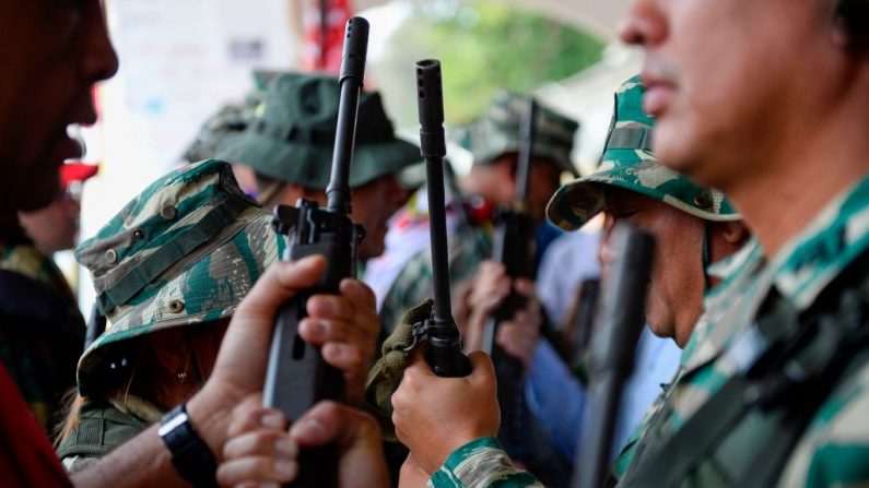Miembros de la Guardia Nacional entregan fusiles a la Milicia Nacional Bolivariana durante los ejercicios militares de activación de las entidades de defensa integral del Estado Miranda. (Créditos MATIAS DELACROIX/AFP vía Getty Images)
