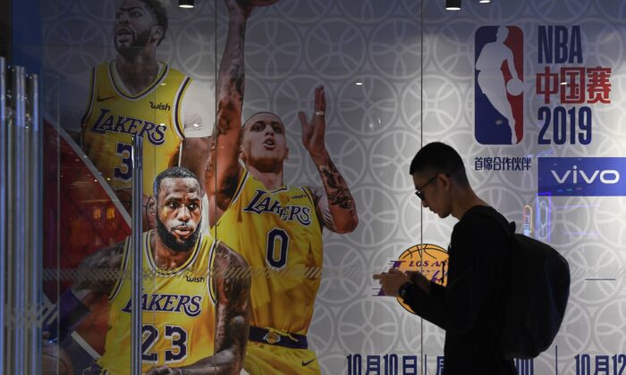 Un hombre pasa junto a un anuncio de juegos de exhibición programados en China entre los LA Lakers y los Brooklyn Nets, en la tienda de la National Basketball Association (NBA) en Beijing el 9 de octubre de 2019. (Greg Baker/AFP vía Getty Images)
