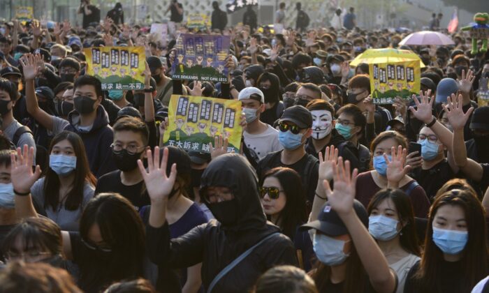 Manifestantes levantan la mano para señalar sus cinco demandas en una marcha en Tsim Sha Tsui, Hong Kong, el 1 de diciembre de 2019. (Gordan Yu/The Epoch Times)