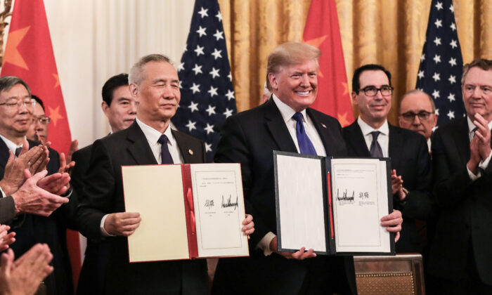 El viceprimer ministro chino Liu He (izq.) y el presidente de Estados Unidos Donald Trump durante la firma de la primera fase de un acuerdo comercial, rodeados de funcionarios, en el Salón Este de la Casa Blanca en Washington el 15 de enero de 2020. (Charlotte Cuthbertson/The Epoch Times)
