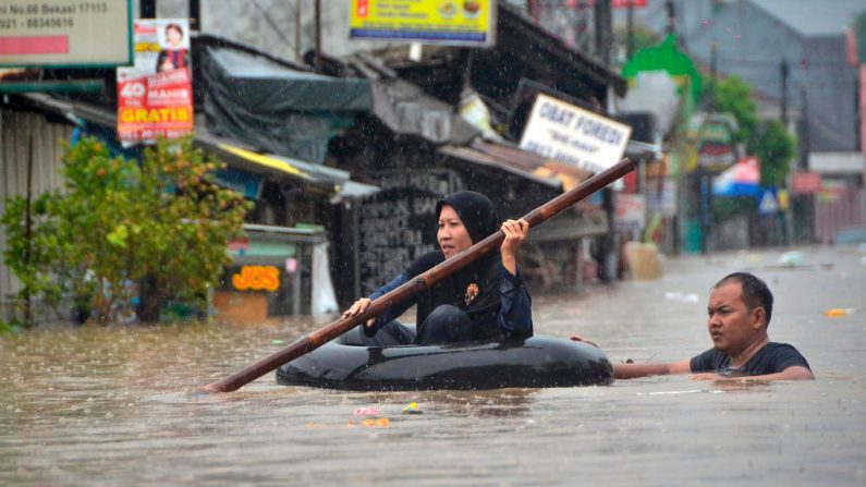 Una mujer cruza un área inundada en una cámara de aire inflada después de que la lluvia causó inundaciones locales en Bekasi, Java Occidental, el 1 de enero de 2020. (REZAS / AFP / Getty Images)
