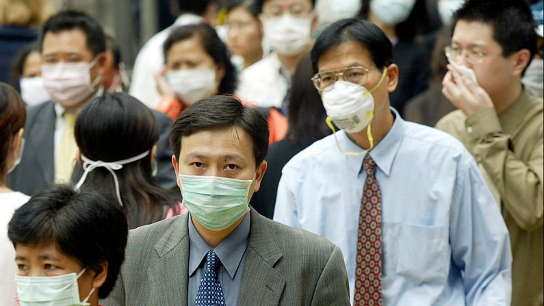 La gente usa máscaras en la calle para protegerse contra un virus mortal de neumonía en Hong Kong, el 31 de marzo de 2003. (PETER PARKS / AFP / GettyImages)