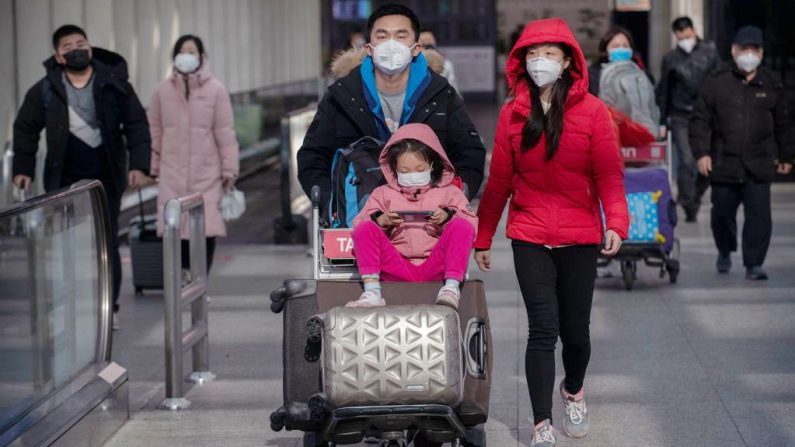 Los pasajeros usan máscaras protectoras mientras caminan con su equipaje en el área de llegadas en el Aeropuerto Capital de Beijing el 30 de enero de 2020 en Beijing, China. (Kevin Frayer / Getty Images)