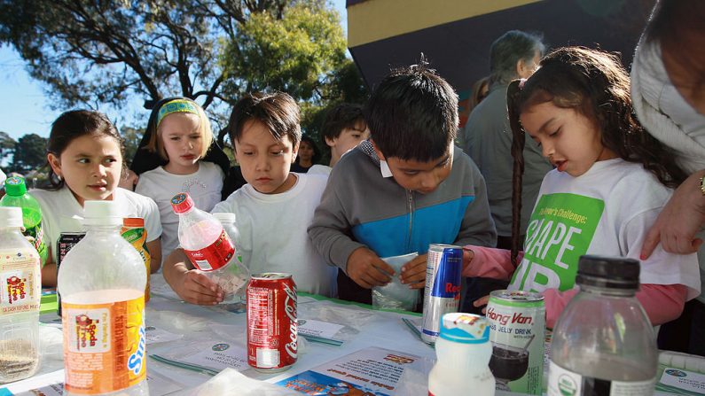Los niños de la Escuela Primaria Fairmount miran una exhibición que muestra cuanta azúcar hay en los refrescos y jugos el 12 de noviembre de 2010 en San Francisco, California. El alcalde de San Francisco Gavin Newsom anunció hoy que vetó una controvertida legislación que fue aprobada por la junta de supervisores de San Francisco que prohibiría los juguetes en las "comidas felices" de comida rápida. Promovió su programa "Shape Up SF" como una forma más eficaz de combatir la obesidad infantil, animando a los niños a comer mejor, a hacer ejercicio y a que las escuelas ofrezcan opciones de alimentos saludables que incluyan verduras frescas. (Justin Sullivan/Getty Images)

