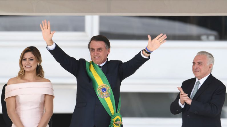 El presidente de Brasil, Jair Bolsonaro (c) saluda a los partidarios junto a su esposa Michelle Bolsonaro (i), luego de recibir la faja presidencial del presidente saliente, Michel Temer, en el Palacio de Planalto en Brasilia el 1 de enero de 2019. (EVARISTO SA/AFP/Getty Images)