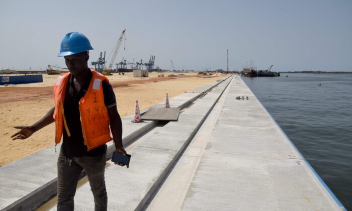 Un técnico trabaja en la construcción de una nueva terminal de contenedores en el puerto de Abidján, el 27 de marzo de 2019. La modernización del puerto de Abiyán, que comenzó en 2012, está dirigida por ingenieros y trabajadores chinos cuyo país financia hasta 1.100 mil millones de Francos CFA de África Occidental (1,67 mil millones de euros). (Issouf Sanogo /AFP vía Getty Images)
