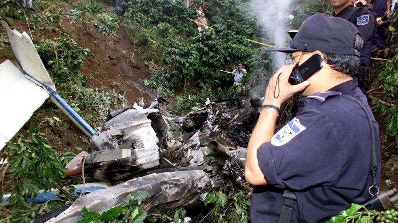 An investigator for the La Policía Nacional Civil habla por teléfono frente a un avión policial que se estrelló el 19 de julio de 2000 en Los Planes de Renderos, El Salvador. (Yuri CORTEZ / AFP / Getty Images)