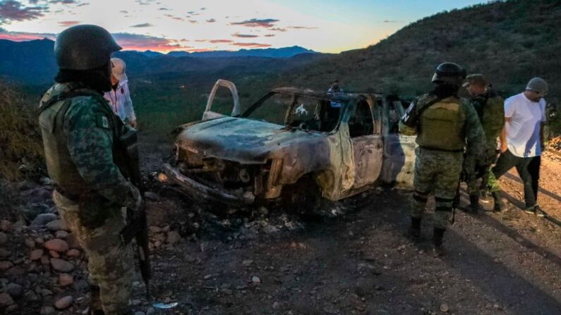 La gente se para cerca del auto quemado, donde parte de los nueve miembros asesinados de la familia Lebaron fueron asesinados y quemados durante una emboscada en Bavispe, montañas de Sonora, México, el 5 de noviembre de 2019. (Herika Martinez/AFP/Getty Images)