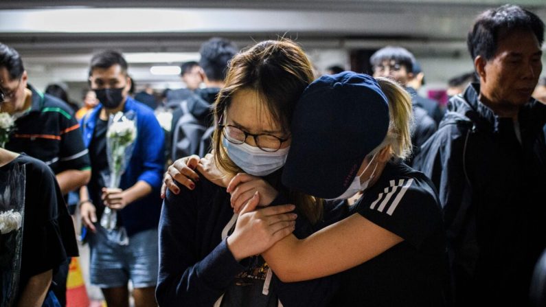 Dolientes reaccionan cuando presentan sus respetos en el estacionamiento donde el estudiante Alex Chow, de 22 años, cayó durante una protesta en el área de Tseung Kwan O en el lado de Kowloon de Hong Kong el 8 de noviembre de 2019. (Anthony Wallace/AFP a través de Getty Images )

