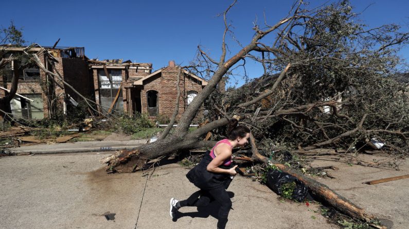Un transeúnte pasa corriendo por un árbol dañado y una casa el 21 de octubre de 2019 en Dallas, Texas. (Ronald Martínez/Getty Images)