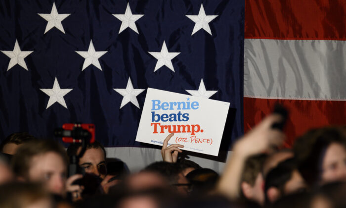 Los partidarios agitan carteles y sostienen sus teléfonos mientras el candidato presidencial demócrata, el senador Bernie Sanders (I-VT), habla en un evento de campaña de Nochevieja el 31 de diciembre de 2019 en Des Moines, Iowa. (Stephen Maturen / Getty Images)