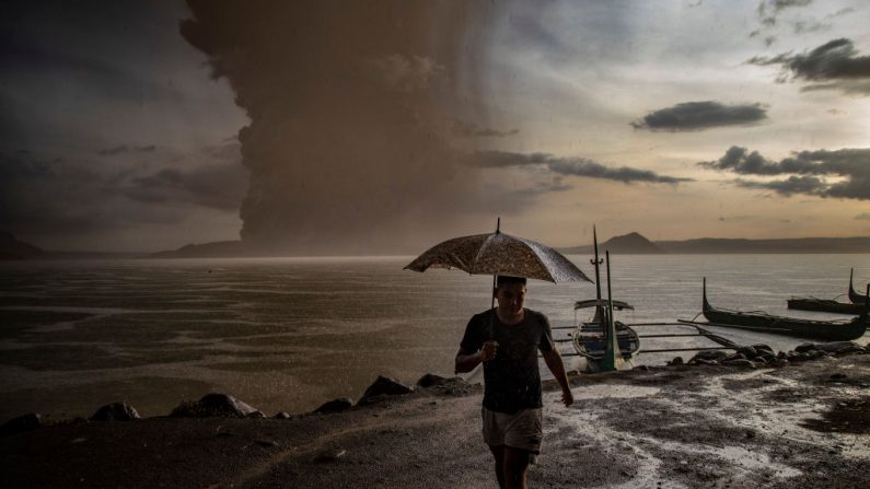 Un residente camina a lo largo de la orilla de un lago mientras el volcán Taal entra en erupción el 12 de enero de 2020 en Talisay, provincia de Batangas, Filipinas. Las autoridades locales han comenzado a evacuar a los residentes cerca del volcán Taal, que comenzó a arrojar cenizas hasta un kilómetro y luego tras violentas explosiones hasta 10 a 15 kilómetros de altura el domingo por la tarde. El Instituto Filipino de Vulcanología y Sismología elevço el nivel de alerta a cuatro de cinco, iniciando evaciaciones masivas. (Ezra Acayan/Getty Images)