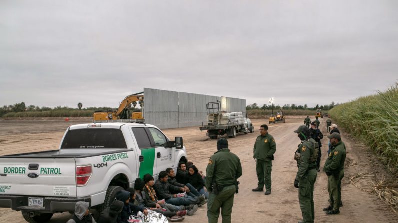 Agentes de la Patrulla Fronteriza de EE.UU. detienen el 11 de diciembre de 2019 a inmigrantes indocumentados atrapados cerca de una sección del muro fronterizo que se está construyendo cerca de Mission, Texas. (John Moore/Getty Images)