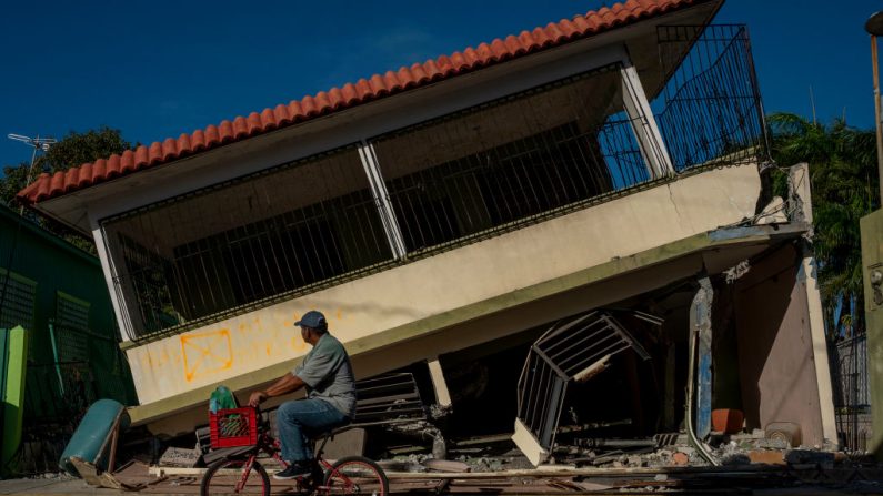 Un hombre monta su pase en bicicleta por una casa derrumbada en Guánica, Puerto Rico, el 15 de enero de 2020, después de que un poderoso terremoto azotara la isla. A partir del 28 de diciembre de 2019, una ola de temblores ha barrido la isla, poniendo nerviosos a los residentes. El terremoto de 6.4 el 7 de enero de 2020 se produjo un día después de un terremoto de magnitud 5.8; fue seguido por grandes réplicas y un terremoto de magnitud 5,9 el 15 de enero de 2020 (RICARDO ARDUENGO / AFP a través de Getty Images)