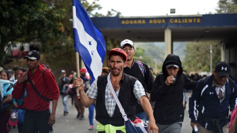 Inmigrantes hondureños con una bandera nacional corren después de atravesar una cerca policial en el cruce fronterizo de Agua Caliente desde Honduras, cerca de Esquipulas, departamento de Chiquimula, Guatemala, el 16 de enero de 2020, en su camino a los EE. UU. (JOHAN ORDONEZ / AFP / Getty Images)