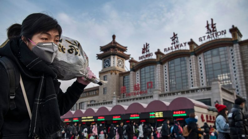 Una mujer china lleva un paquete cuando llega a la estación de tren de Beijing antes de abordar un tren antes del Festival de Primavera anual el 21 de enero de 2020 en Beijing, China. (Kevin Frayer/Getty Images)