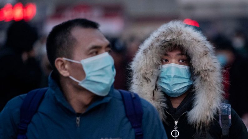 Los viajeros chinos usan máscaras protectoras cuando llegan a abordar los trenes en la estación de trenes de Beijing antes del Festival de Primavera anual el 21 de enero de 2020 en Beijing, China. (Kevin Frayer/Getty Images)