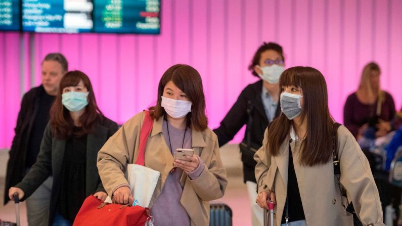 Los pasajeros usan máscaras para protegerse contra la propagación del Coronavirus cuando llegan al Aeropuerto Internacional de Los Ángeles, California, el 22 de enero de 2020. (MARK RALSTON / AFP / Getty Images)