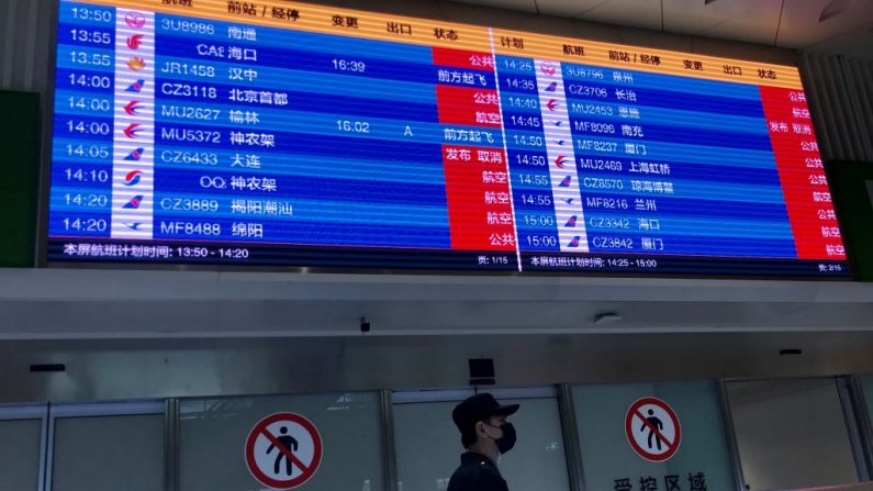 Un hombre con mascarilla merodea debajo de una pantalla que muestra los vuelos cancelados en el aeropuerto de Tianhe en Wuhan, en la provincia central de China, Hubei, el 23 de enero de 2020. (Foto de LEO RAMIREZ/AFP vía Getty Images)