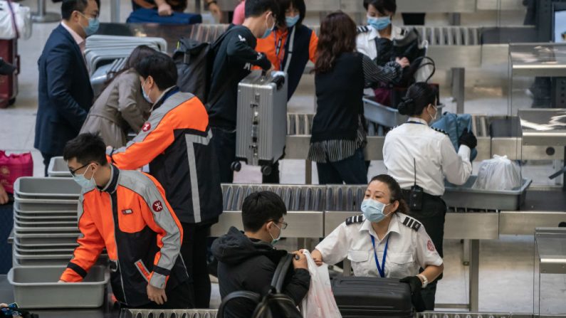 Los funcionarios de seguridad con máscaras faciales revisan las pertenencias de los viajeros dentro de la sala de embarque de la estación West Kowloon el 23 de enero de 2020 en Hong Kong, China. (Anthony Kwan / Getty Images)