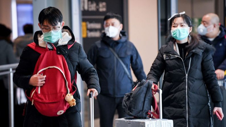 Los pasajeros procedentes de China, salen de la Terminal con máscaras de papel después de aterrizar en el Aeropuerto Charles De Gaulle el 26 de enero de 2020 en Roissy-en-France (Francia). (ALAIN JOCARD / AFP / Getty Images)