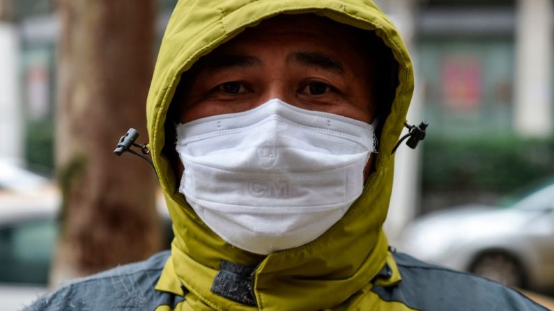 Un hombre que trabaja como voluntario dando medicamentos para quienes los necesitan espera fuera de una farmacia en Wuhan el 26 de enero de 2020, una ciudad en el epicentro de un brote viral que ha matado al menos a 56 personas e infectado a casi 2000. (HECTOR RETAMAL/AFP vía Getty Images)