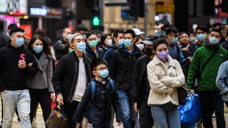 Los peatones que llevan máscaras faciales cruzan una calle durante un feriado público del Año Nuevo Lunar en Hong Kong el 27 de enero de 2020, como medida preventiva luego de un brote de coronavirus que comenzó en la ciudad china de Wuhan. (ANTHONY WALLACE / AFP / Getty Images)