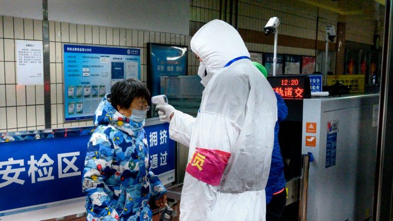 Un personal de seguridad que usa ropa protectora para ayudar a detener la propagación de un virus mortal similar al SARS que se originó en la ciudad central de Wuhan verifica la temperatura de un pasajero en la entrada de la estación de metro en Beijing el 28 de enero de 2020. El nuevo coronavirus mortal que ha estallado en China, 2019-nCoV, afectará a un mínimo de decenas de miles de personas y durará al menos varios meses, estiman los investigadores según los primeros datos disponibles. (NOEL CELIS / AFP a través de Getty Images)
