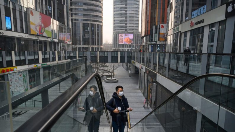 Un hombre chino lleva una máscara protectora mientras sube por una escalera mecánica en una gran zona comercial vacía que normalmente estaría ocupada durante la festividad del Año Nuevo y el Festival de Primavera chinos el 28 de enero de 2020 en Beijing, China. (Foto de Kevin Frayer/Getty Images)