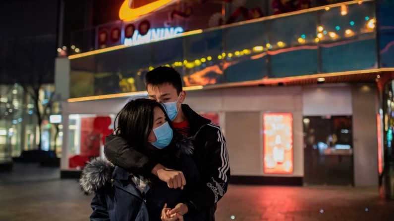 Una pareja se abraza en un centro comercial vacío en el área de Sanlitun en Beijing el 28 de enero de 2020. (NIcholas Asfouri / AFP a través de Getty Images)