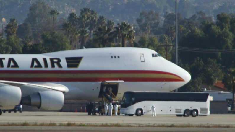 El personal en trajes de riesgo biológico recibe a los pasajeros evacuados de Wuhan en Riverside, California, el 29 de enero de 2020. (MATT HARTMAN/AFP a través de Getty Images) 