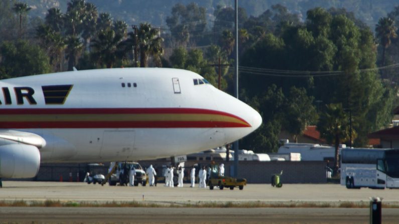 El personal en trajes de riesgo biológico aguarda a los pasajeros evacuados de Wuhan, la ciudad china en el corazón de un brote creciente del mortal Coronavirus Novel 2019, poco después de que el avión aterrizó en la Base de la Reserva Aérea March en Riverside, California (EE.UU.), el 29 de enero de 2020. (MATT HARTMAN / AFP / Getty Images)