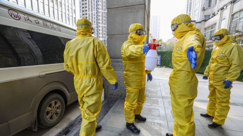 Esta foto, tomada el 30 de enero de 2020, muestra a los miembros del personal de una funeraria con trajes protectores desinfectando a un colega tras haber trasladado un cuerpo en un hospital de Wuhan en la provincia central de Hubei, China, durante el brote de virus en la ciudad. (Foto por STR/AFP vía Getty Images)