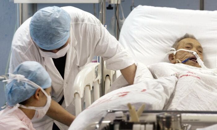 Enfermeras tratan a un paciente por una dolencia desconocida en la unidad de cuidados intensivos del Hospital Nº. 1 de Guangzhou, China, el 12 de junio de 2003. (PETER PARKS/AFP/GettyImages)