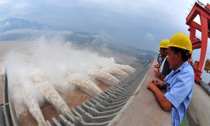 Trabajadores observan el agua liberada de la Presa de las Tres Gargantas, un gigantesco proyecto hidroeléctrico en el río Yangtze en Yichang, en la provincia de Hubei, en el centro de China, el 24 de julio de 2012. (STR/AFP/GettyImages)

