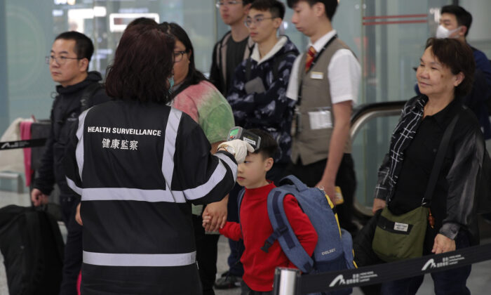 Um oficial de vigilância sanitária usa um dispositivo para verificar a temperatura dos passageiros perto dos balcões de imigração no aeroporto internacional de Hong Kong, em 4 de janeiro de 2020 (AP Photo / Andy Wong)