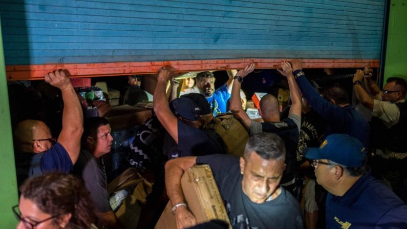 La policía se aproxima mientras la gente irrumpe en un almacén lleno de suministros en Ponce, Puerto Rico, el 18 de enero de 2020. (Ricardo Arduengo/AFP/Getty Images)