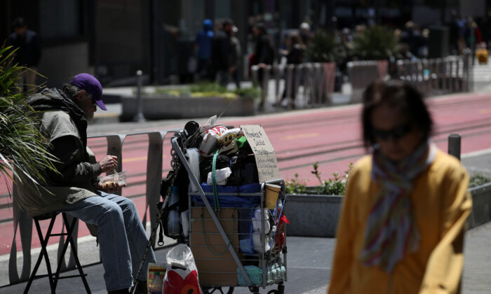 Un peatón camina junto a un hombre sin hogar que pide dinero el 17 de mayo de 2019 en San Francisco, California (Justin Sullivan/Getty Images) 