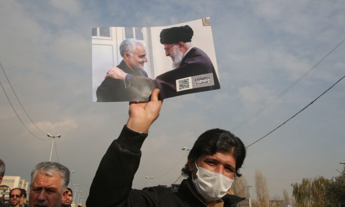 Un hombre sostiene una foto del líder supremo de Irán, el ayatola Alí Khamenei, con el general de división Qassem Soleimani (Izq.) de la Guardia Revolucionaria de Irán durante una manifestación en Teherán el 3 de enero de 2020.  (Atta Kenare/AFP vía Getty Images)