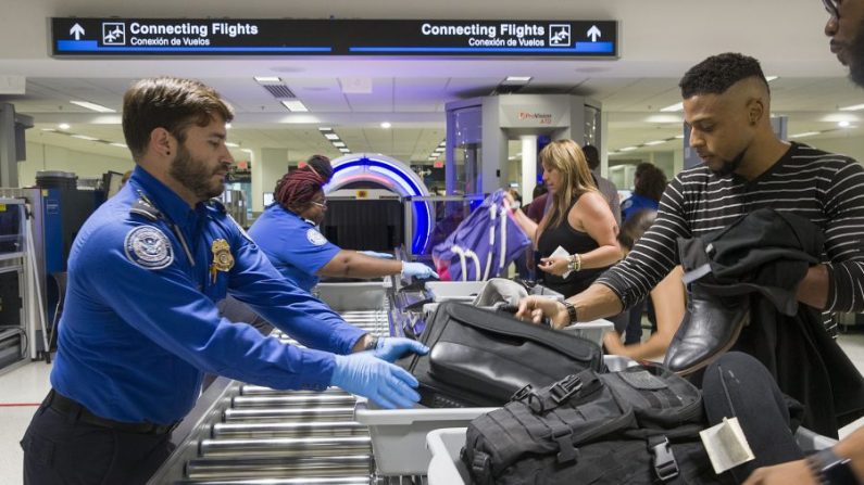 Los agentes de la Administración de Seguridad en el Transporte (TSA) ayudan a los viajeros a colocar sus bolsas a través del escáner tridimensional en el Aeropuerto Internacional de Miami el 21 de mayo de 2019 en Miami, Florida (Joe Raedle/Getty Images)