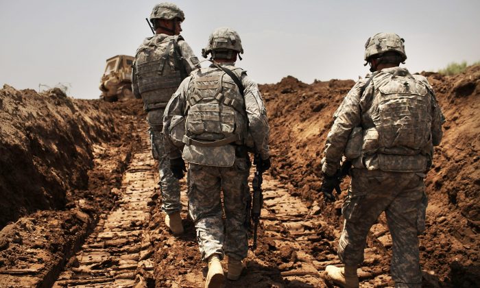 Soldados estadounidenses con el 3er Regimiento de Caballería Blindada patrullan una nueva zanja que han cavado para proteger la base del ataque en Iskandariya, provincia de Babil, Irak, el 19 de julio de 2011. (Spencer Platt / Getty Images)