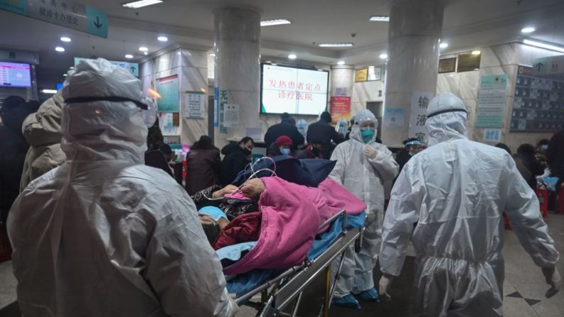 Personal médico que lleva ropa de protección contra un coronavirus previamente desconocido llega con un paciente al Hospital de la Cruz Roja de Wuhan
(RETAMAL DE HECTORES/AFP a través de Getty Images)