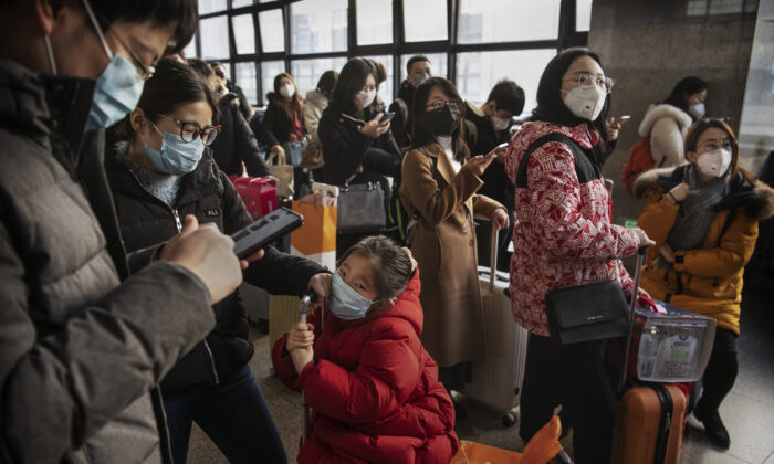 Viajeros chinos usan máscaras protectoras mientras esperan para subir a un tren antes del Festival de Primavera anual en una estación de ferrocarril de Beijing, China, el 23 de enero de 2020. (Kevin Frayer/Getty Images)