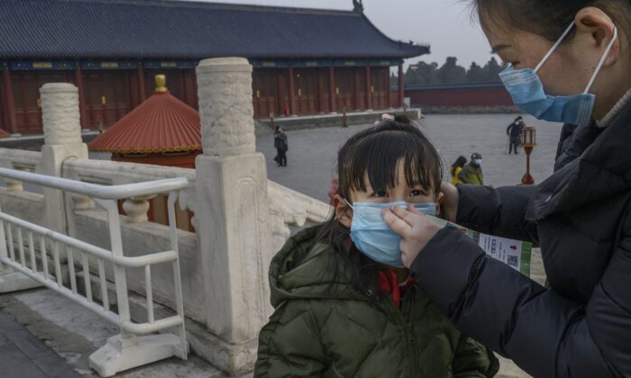 Una joven turista china lleva una máscara protectora mientras recorre los terrenos casi vacíos del Templo del Cielo en Beijing, China, el 27 de enero de 2020. (Kevin Frayer/Getty Images)
