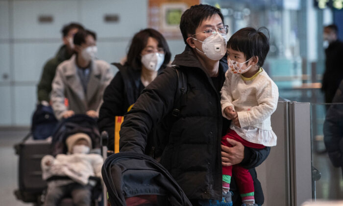 Pasajeros usan máscaras protectoras mientras caminan con su equipaje en el área de llegadas del Aeropuerto Capital de Beijing, el 30 de enero de 2020. (Kevin Frayer / Getty Images)