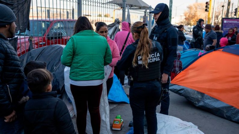 La policía municipal de Juárez habla con los solicitantes de asilo acampados cerca del puente internacional de Paso del Norte, tratando de convencerlos de que acudan a los refugios para inmigrantes que se encuentran en los alrededores de la ciudad el 19 de diciembre de 2019 en Ciudad Juárez, México. (PAUL RATJE/AFP vía Getty Images)